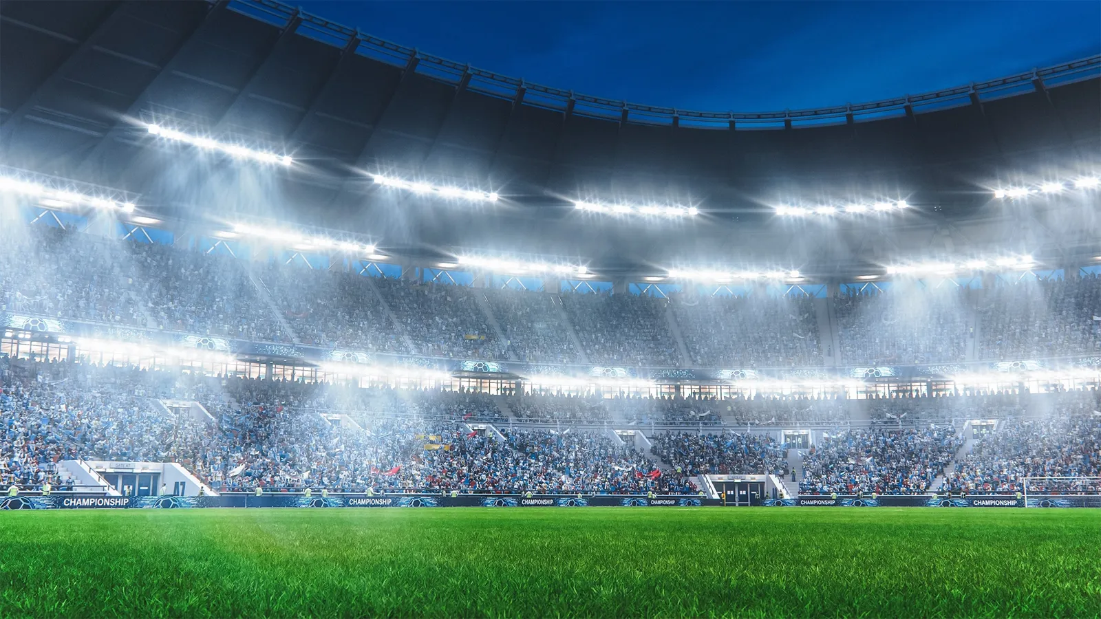 View from field of soccer stadium at night with crowd in distance and bright lights